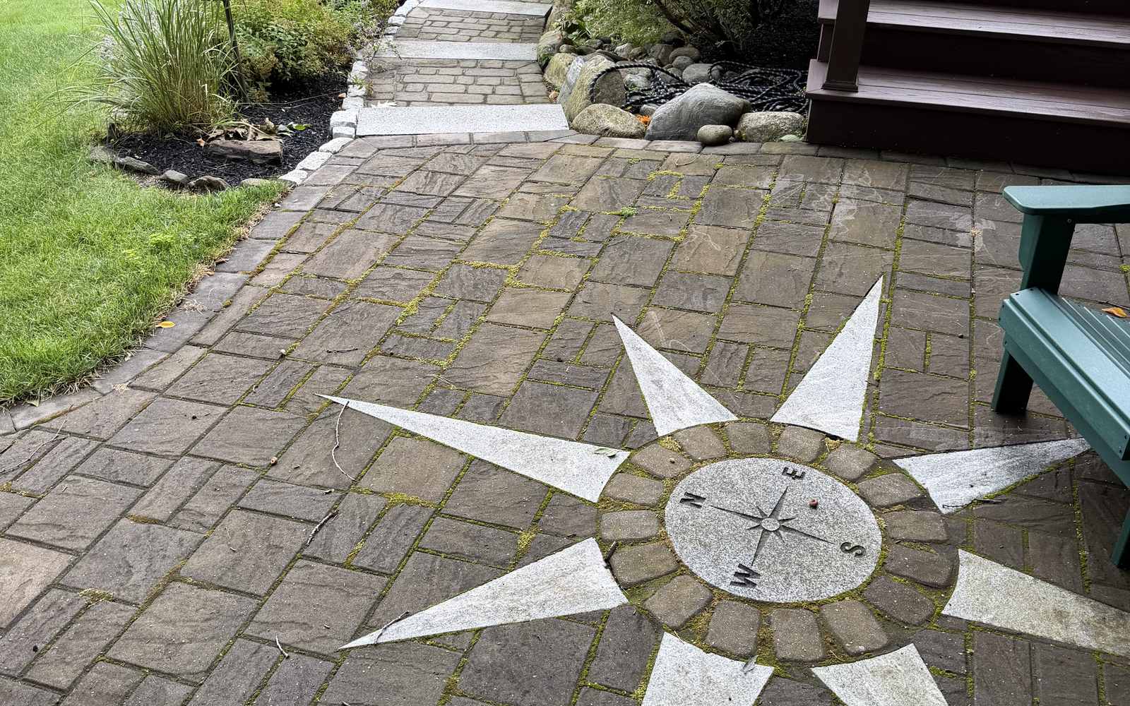 Stone patio with a compass medallion inlay and paver walkway built by Expert Lawn & Landscape in Cumberland, Maine