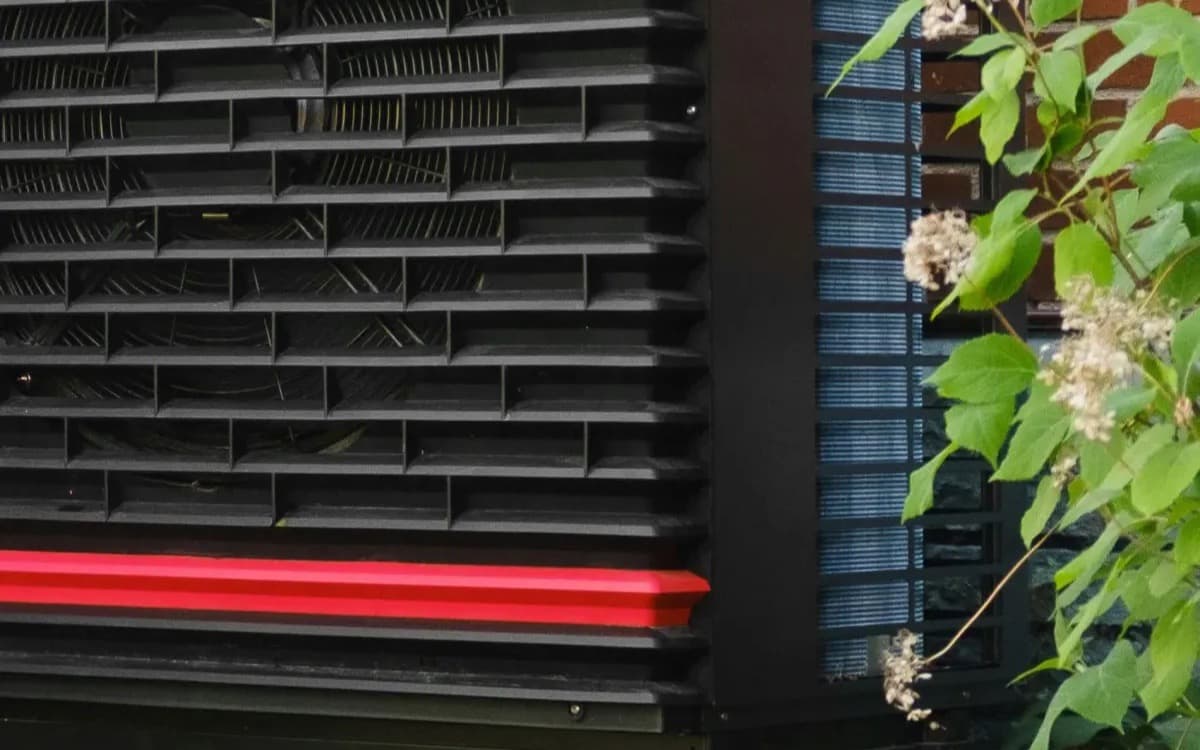 Outdoor heat pump unit mounted beside a brick building