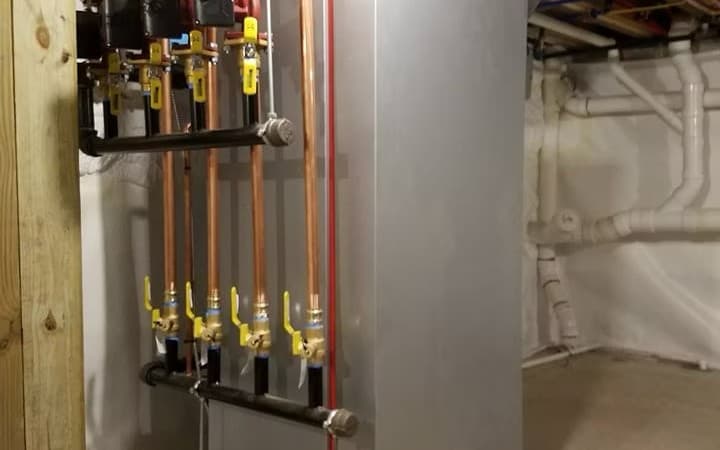 Technician's boiler and copper piping installation in a Maine basement, Knowles Mechanical