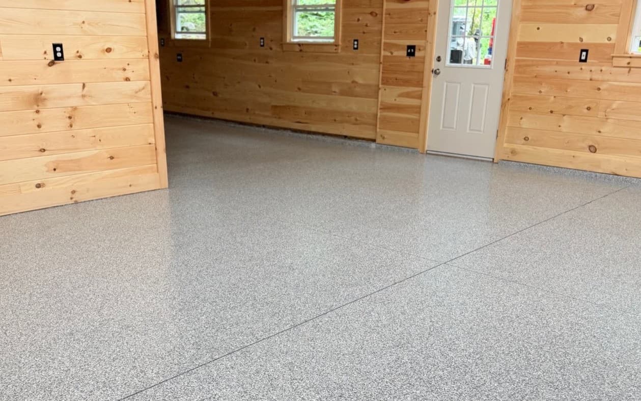 Finished light gray flake epoxy garage floor with wood-paneled walls, installed by Southern Maine Epoxy
