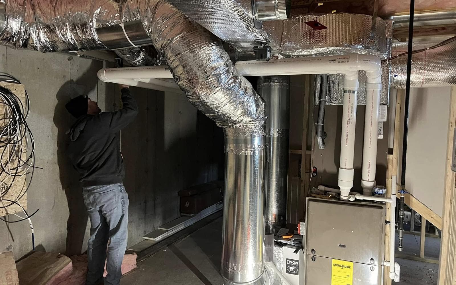 Technician installing ductwork for a residential heat pump system, Southern Maine Heat Pumps
